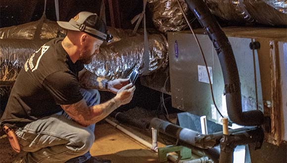 Blake Miller, from Top 2 Bottom Inspections, checking the HVAC system in an attic during a home inspection in Brazoria County.