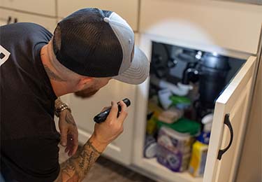 A home inspector checking the kitchen plumbing.